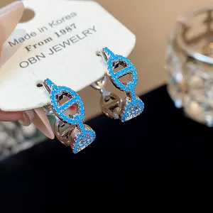 Detailed view of silver hoop earrings with blue zircon in vintage pig nose design