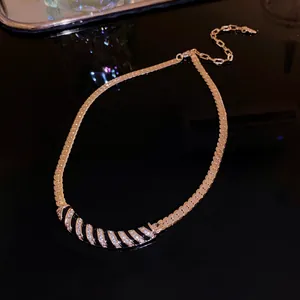 Close-up of gold-plated necklace featuring a curved rhinestone and black striped pendant.