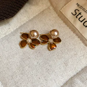 Macro detail of zircon flower and pearl earrings with rich brown enamel petals