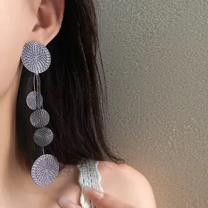 Detailed macro shot of elegant silver tassel earrings with textured round discs on ear