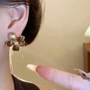 Close-up detail of elegant floral stud earring featuring a gold pearl and sparkling zircons