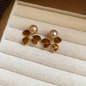 Close-up of elegant zircon flower pearl stud earrings in a beige corduroy jewelry box