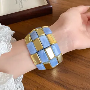 Dettaglio di un bracciale in acrilico marmo blu e metallo dorato rettangolare