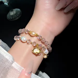 Elegante bracciale a due strati con pietre occhio di gatto, cristalli e perle al polso.