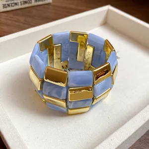 Dettaglio di un bracciale chunky in acrilico blu marmorizzato e patchwork dorato nel vassoio