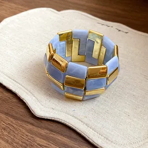 Primo piano di bracciale elastico in acrilico blu e blocchi di metallo dorato