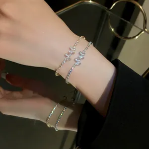 Close-up detail of two elegant zirconia butterfly bracelets worn on a wrist with mirror reflection