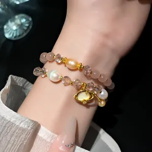 Primo piano di bracciale con perle e cristalli e ciondolo occhio di gatto sul polso.