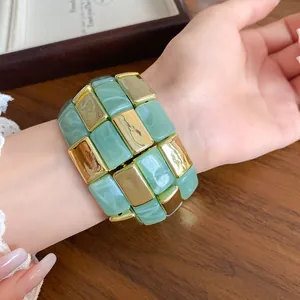 Dettaglio ravvicinato di un ampio bracciale a maglie quadrate in acrilico verde e oro