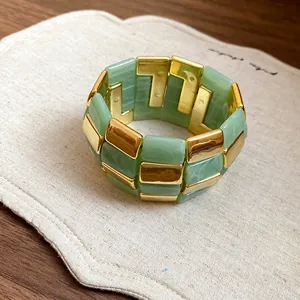 Primo piano di un bracciale di lusso in acrilico con inserti verde giada e dorati