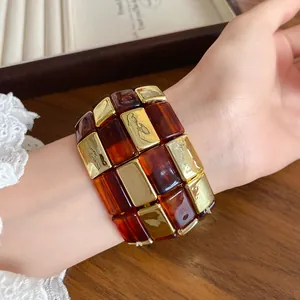 Dettaglio ravvicinato di un bracciale vintage in acrilico ambra e in tonalità oro.