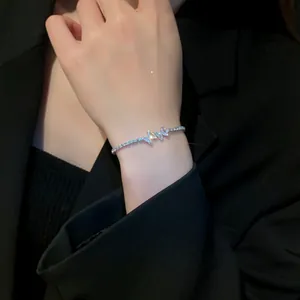 Macro detail view of a dainty silver-tone zircon butterfly bracelet worn on a female wrist