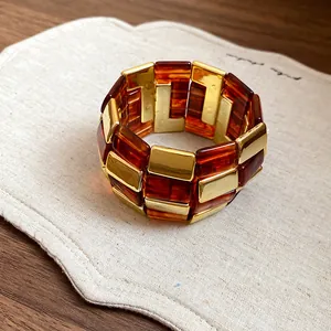 Primo piano dettagliato della trama del bracciale in acrilico ambrato e metallo dorato.