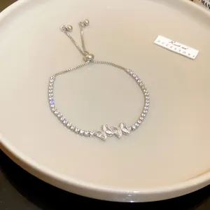 Detail of elegant silver zircon butterfly adjustable bracelet on ceramic tray.