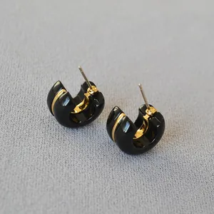 Close-up view of elegant black enamel C-shaped hoop earrings with gold-plated accents