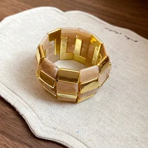 Dettaglio del bracciale a maglie quadrate in acrilico oro e beige su lino