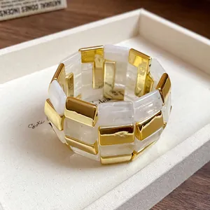 Dettaglio di blocchi di acrilico bianco e oro su un bracciale patchwork chic