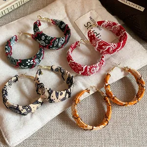 Detailed view of four pairs of stylish fabric-wrapped hoop earrings with colorful paisley patterns
