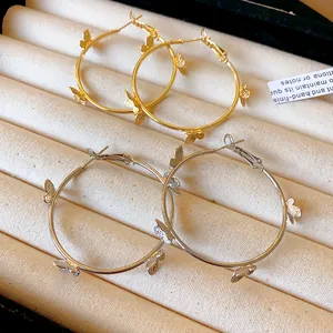 Vue détaillée de boucles d'oreilles créoles papillon en or et argent sur un plateau