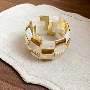 Dettaglio macro di un lussuoso bracciale in acrilico a maglie quadrate oro e bianco