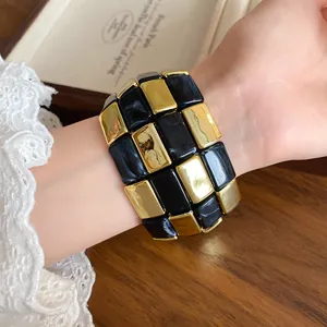 Dettaglio di un bracciale chic in acrilico con tessere marmorizzate oro e nere.