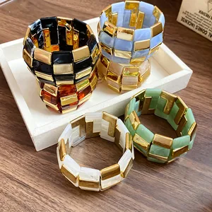 Primo piano di bracciali colorati in acrilico e metallo dorato su un vassoio da esposizione