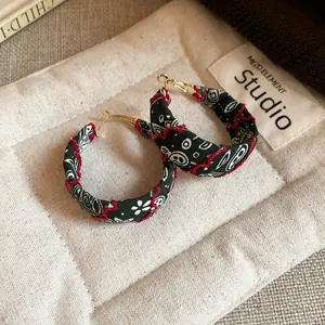 Close-up of bohemian fabric printed hoop earrings with red wave stitching detail