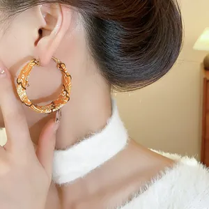 Macro view of stylish hoop earrings wrapped in orange floral fabric on female model
