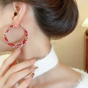 Detailed view of red and white fabric printed hoop earrings worn by an Asian model