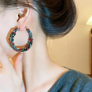 Detail view of large fabric hoop earrings with paisley print and red decorative stitching