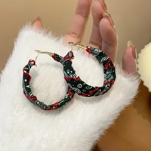 Detailed view of fabric-wrapped hoop earrings with red embroidery and paisley pattern.