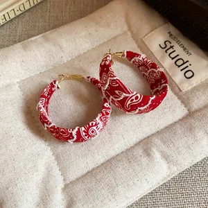 Close-up of red paisley print fabric hoop earrings with gold-tone hardware