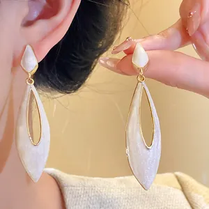 Close-up of elegant hollow teardrop earrings with white shimmer drip oil finish.