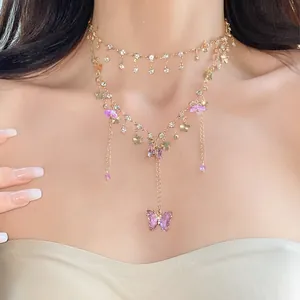 Detailansicht einer mehrlagigen Goldkette mit funkelnden Schmetterlingen und Blumen.