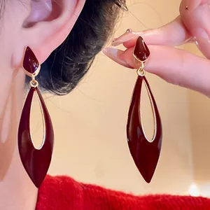 Close-up detail of burgundy enamel hollow waterdrop earrings with retro gold trim