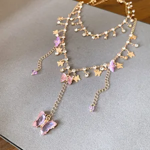 Detailansicht einer mehrlagigen Goldkette mit rosa Schmetterlingsanhängern und Strass.