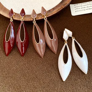 Macro view showing vintage hollow teardrop enamel earrings in burgundy brown and pearl white