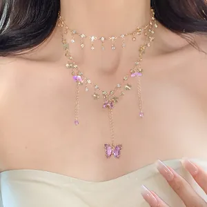 Nahaufnahme einer mehrlagigen Goldkette mit Strasssteinen und violetten Schmetterlingen