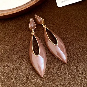 Close-up of Maillard brown enamel water drop dangle earrings with gold hollow design.