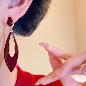 Macro detail shot showing the elegant vintage burgundy enamel hollow teardrop earrings on model