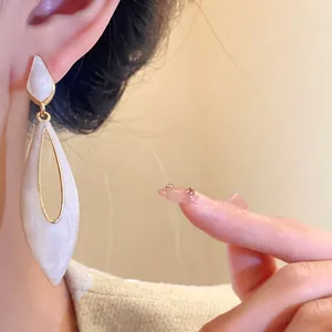 Detailed view of elegant pearlescent white waterdrop cutout earrings on a model
