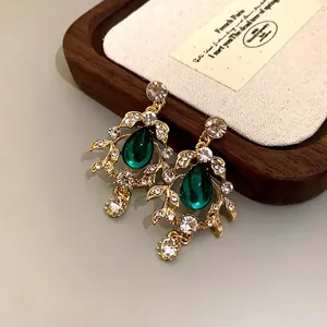 Elegant vintage emerald teardrop earrings with gold leaf accents and sparkling crystals