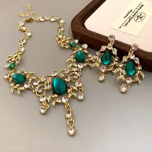 Close-up of vintage gold-tone emerald teardrop pendant necklace and matching earring set