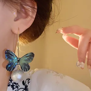 Elegant forest style butterfly pearl earrings featuring iridescent wings and gold hoop hooks