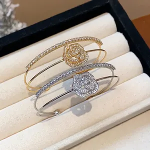 Elegant double-layered gold and silver open bracelets with zircon flower motifs on a tray