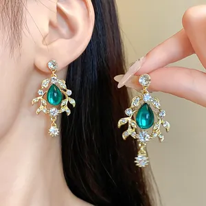 Vintage palatial gold leaf earrings with emerald green teardrop stones and rhinestones.