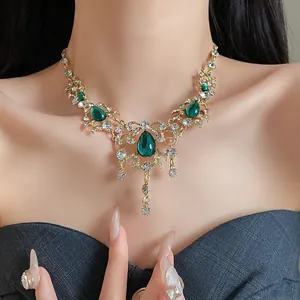 Detail view of a vintage gold-toned necklace with green teardrop stones on a model.