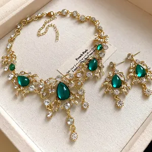 Macro detail of a vintage jewelry set with emerald green teardrop stones and gold leaves