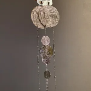 Macro view of stylish silver long tassel earrings featuring concentric textured metal discs.