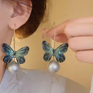 Close-up view of butterfly drop earrings with gradient wings and textured silver beads